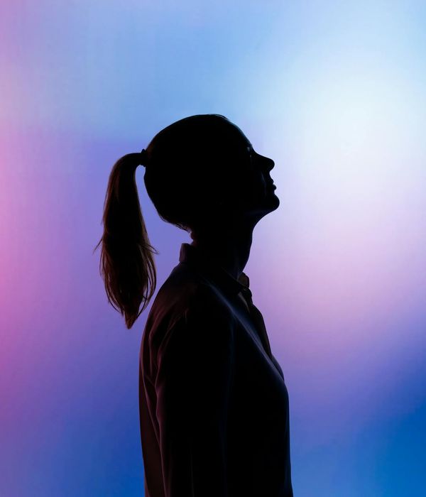 Woman in a calming yoga pose against a pastel pink background